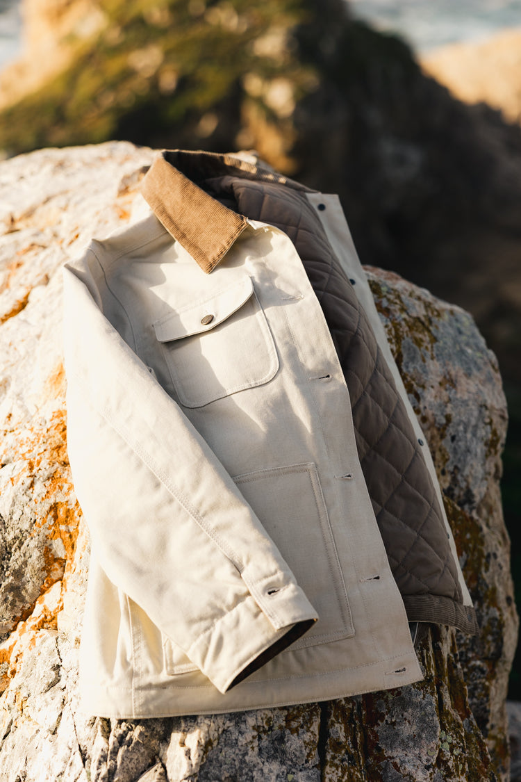 Inside view of the Rancher Jacket showing the diamond-patterned insulated quilting and durable cream canvas exterior with a corduroy collar.