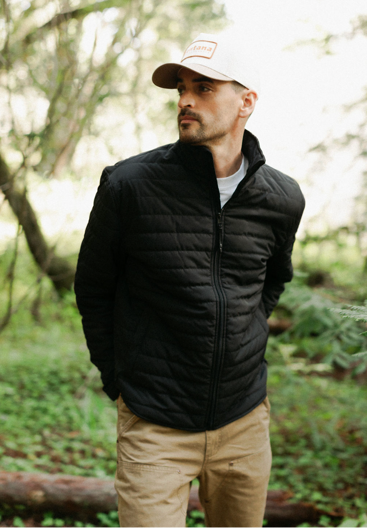 Men’s Draftsman Pant in salt washed Tobacco featuring double-front utility panels, styled with the black Stillwater Jacket for a rugged outdoor look.