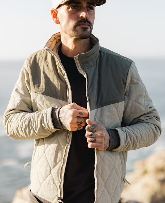 Men’s two-tone Cruzer jacket featuring olive green shoulder panels, cream diamond quilting, and a zip-up mock neck.