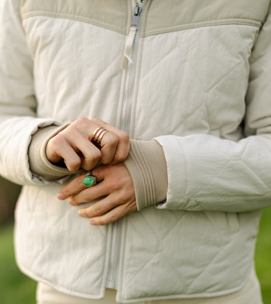 Close-up of the women's cream Cruiser jacket featuring a heavy-duty zipper with pull tab, wide ribbed knit cuffs, and diamond-pattern quilting.