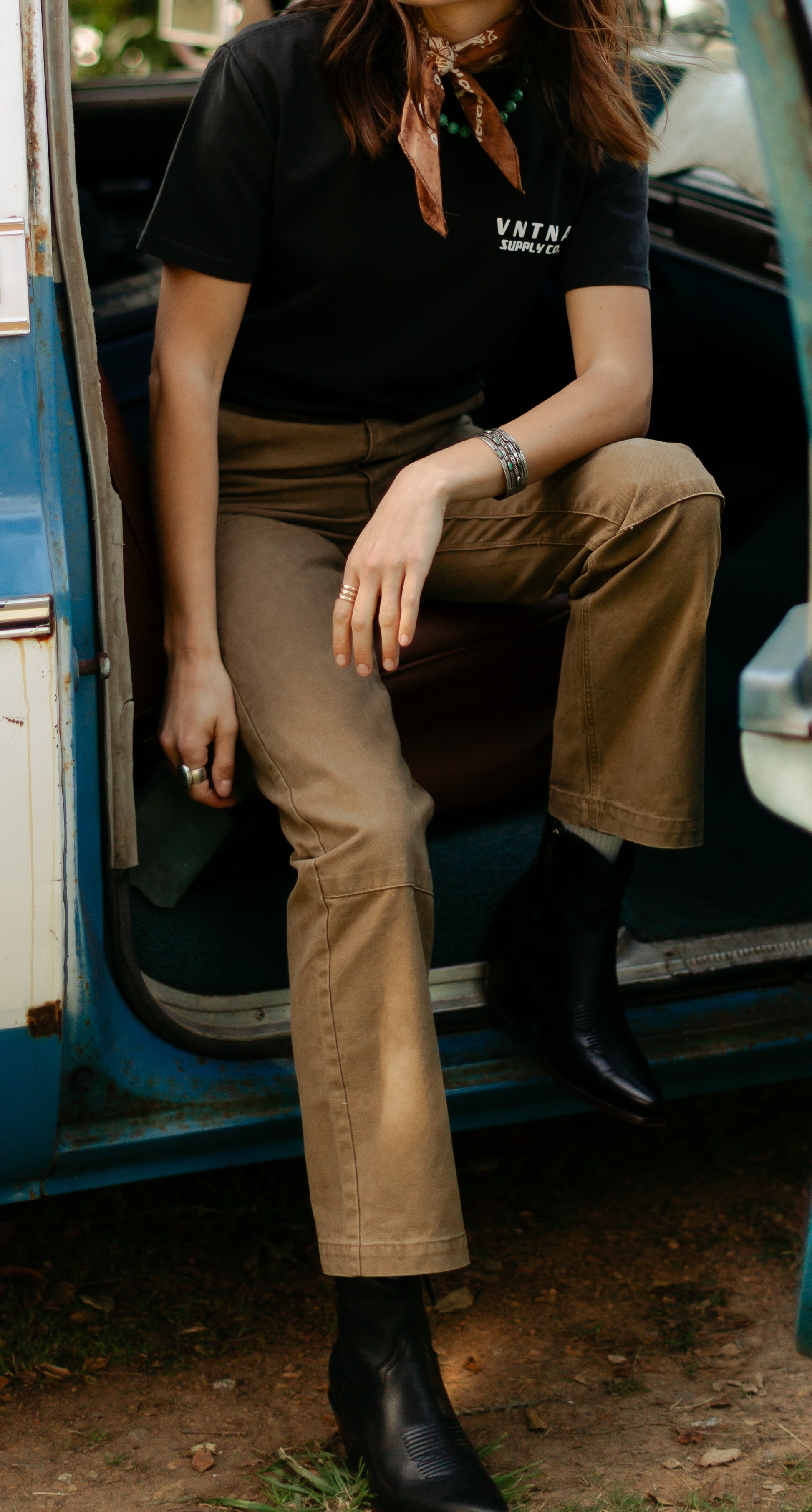 Seated view of the women's Lily Pant in Tobacco brown, highlighting the double-knee reinforcement panels and durable 100% cotton canvas construction.