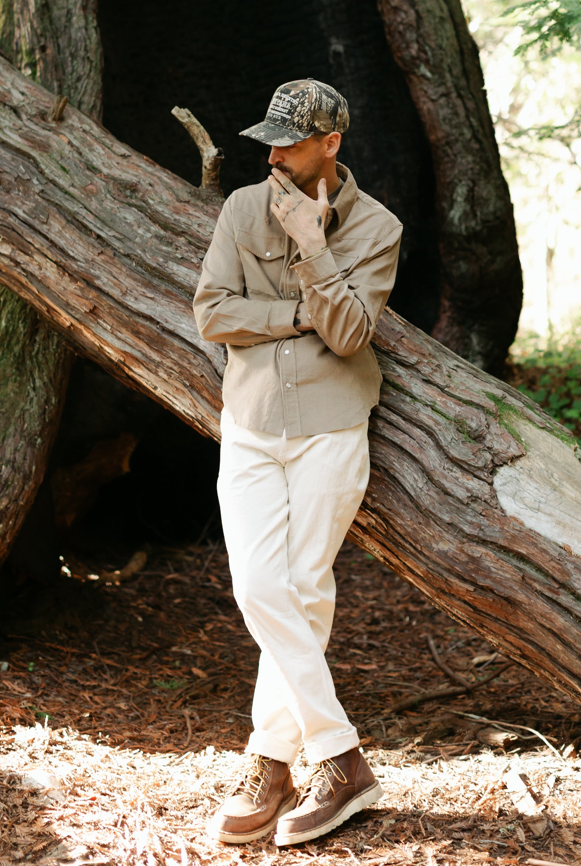Men’s Tradesman Pant in Ivory cotton canvas, styled with the Dusty Olive Western Cord Shirt and a camo trucker hat for a rugged heritage outdoor look.