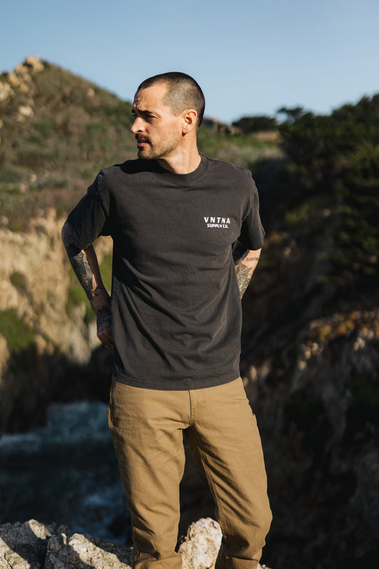 Men’s Tradesman Pant in salt washed Tobacco, featuring a durable 100% cotton canvas build, styled with a charcoal VNTNA Supply Co. graphic tee.
