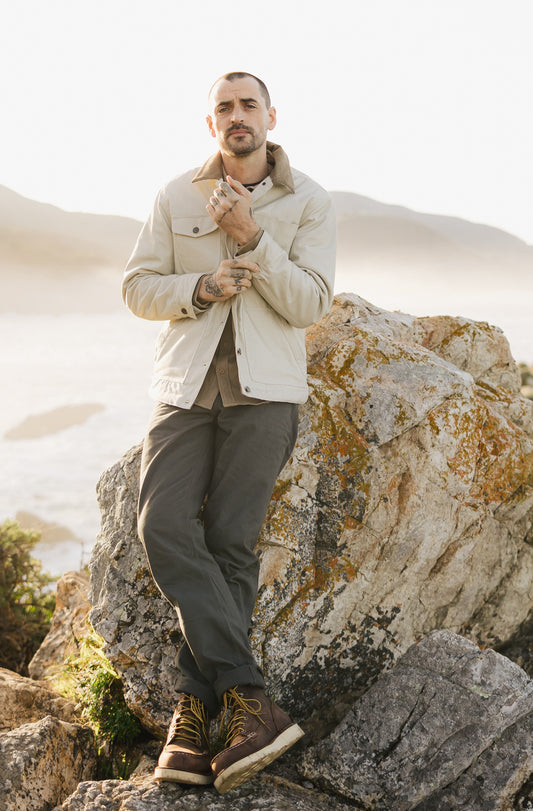 Men’s Tradesman Pant in Vintage Coal 100% cotton canvas, styled with the cream Arroyo Rancher Jacket and brown work boots for a rugged coastal workwear aesthetic.