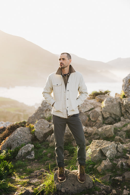 Men’s Tradesman Pant in Vintage Coal styled with a cream Arroyo Rancher Jacket, showcasing a durable 100% cotton canvas build and straight-leg fit for rugged coastal outdoor wear.